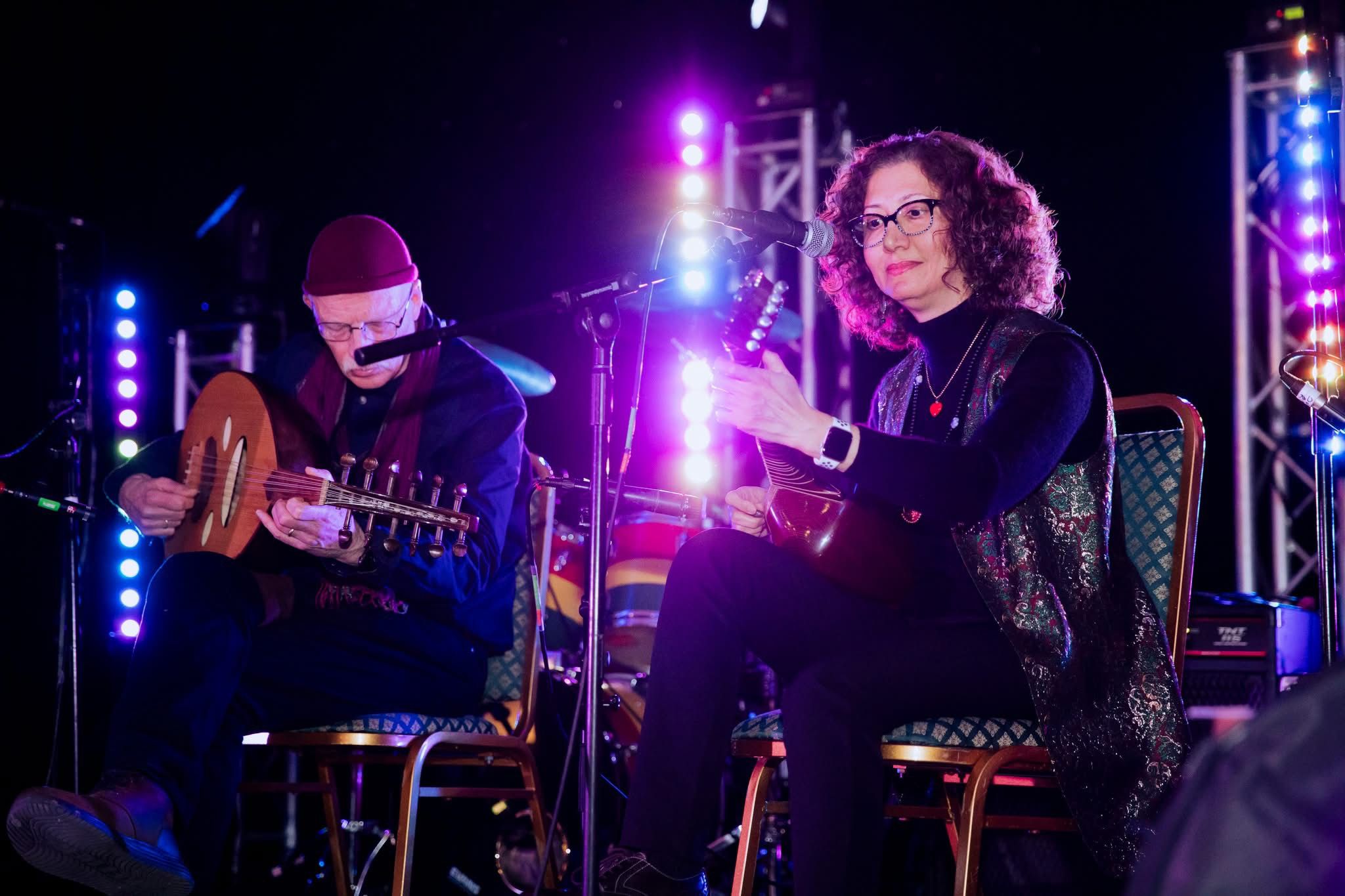 Two musicians playing oud instruments on stage at the SRACA gala