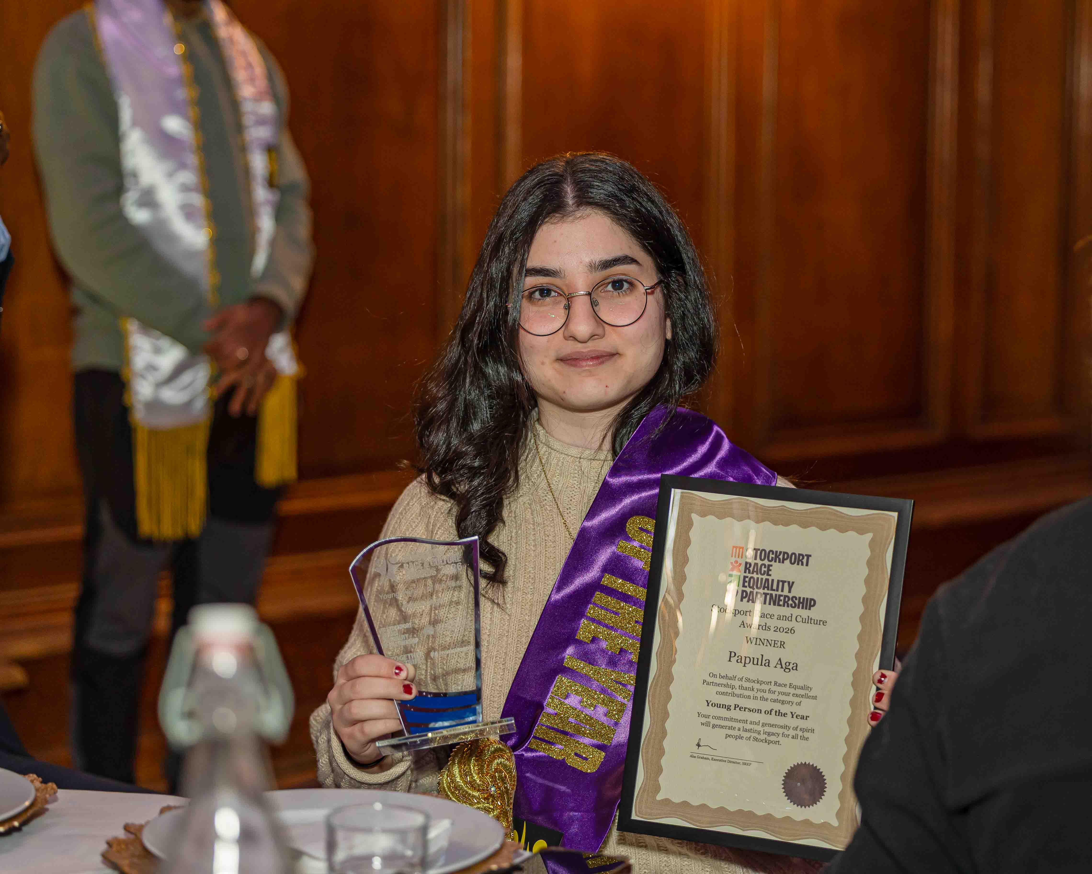 A young winner holding her SRACA award and certificate